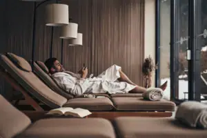 A man in a bathrobe is lying on a couch.