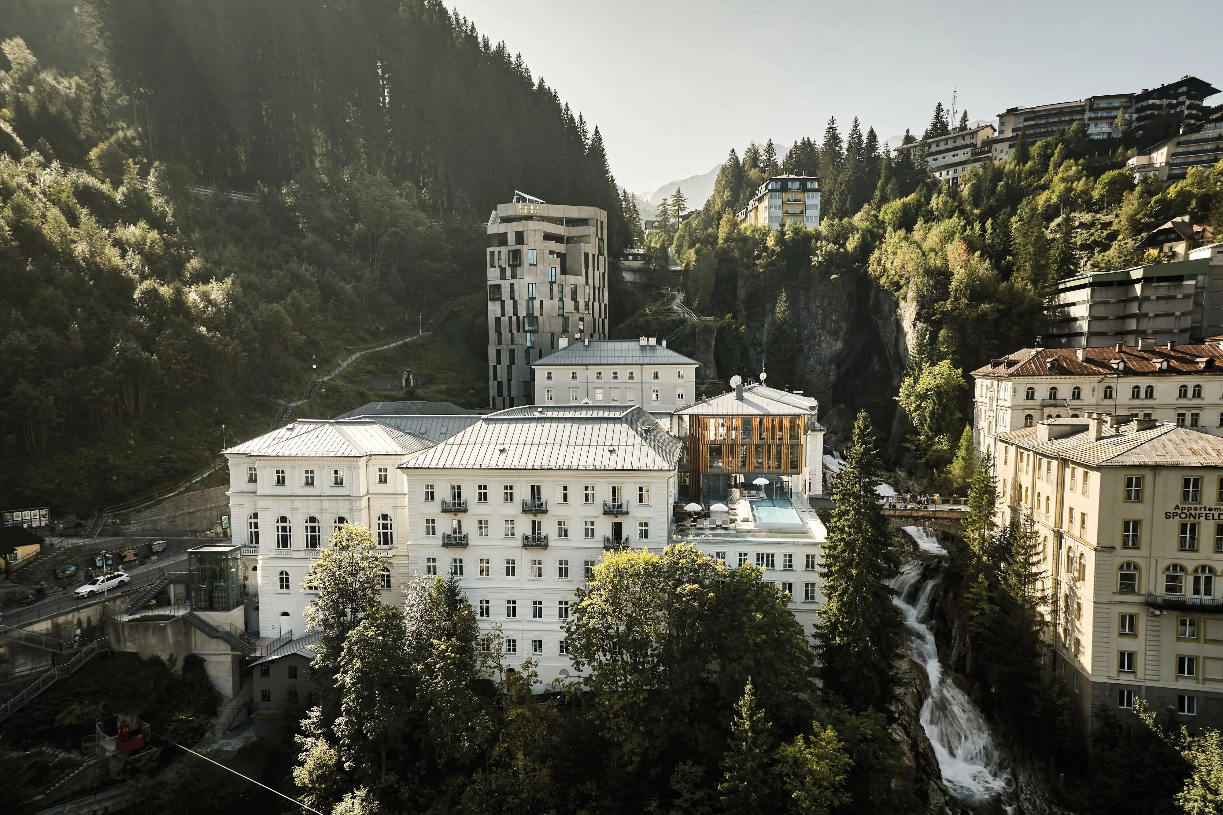 A group of buildings nestled in a valley with trees and a clear sky.