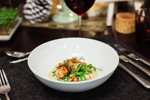 A bowl of food and a glass of wine.