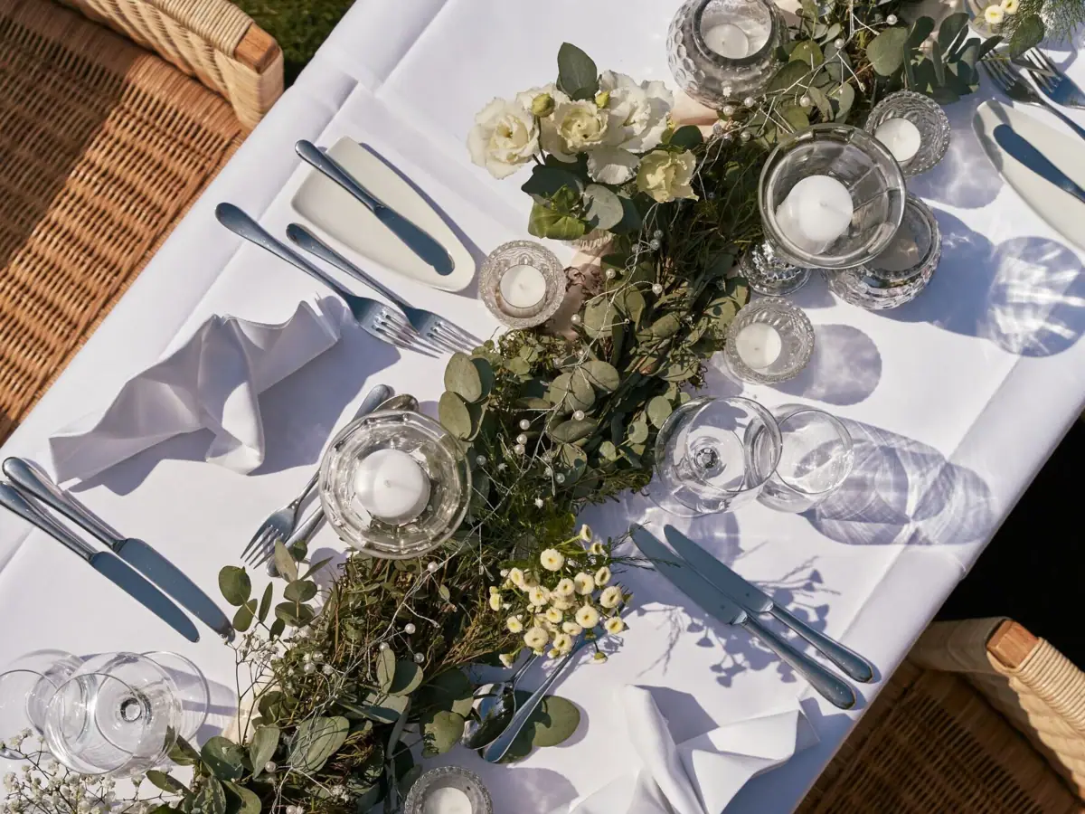 A table with a floral arrangement and lit candles.