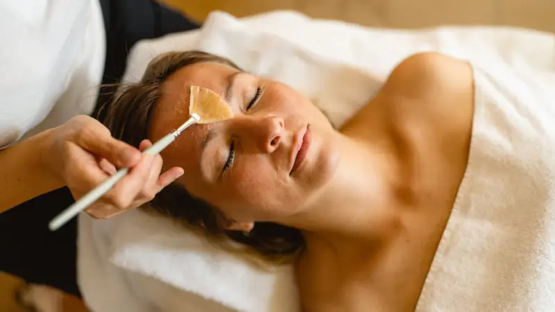 A woman is lying there, relaxed, whilst a brush touches her face.