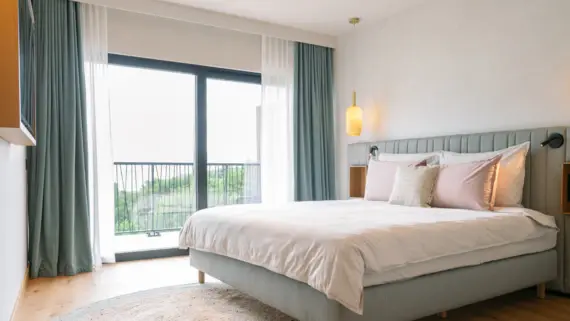 Comfortably arranged bed with pillows on a balcony-facing room in a boutique hotel.