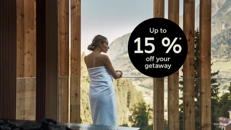 A woman wrapped in a towel is looking out of the window.