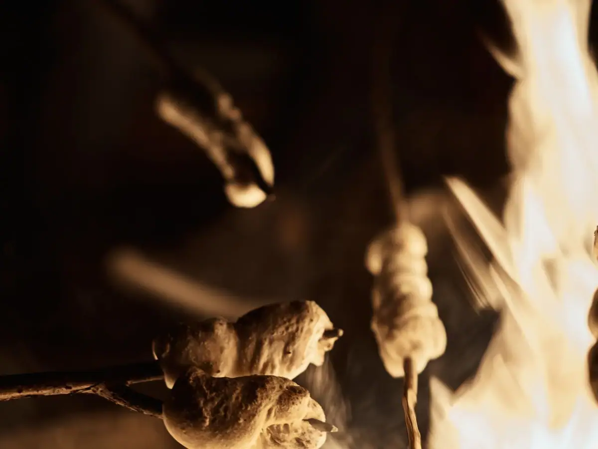 Food on sticks roasting over an open fire.