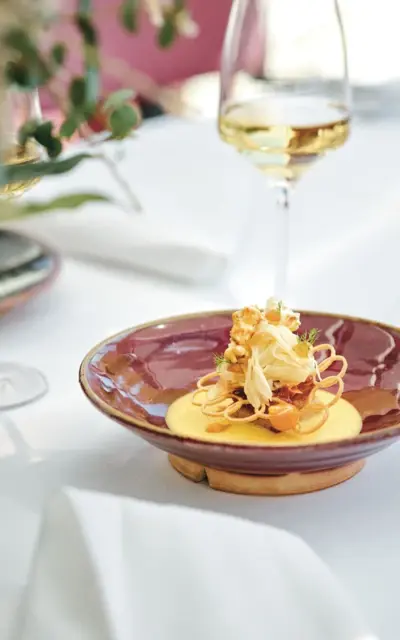 A plate of food on a table, surrounded by wine glasses and cutlery.