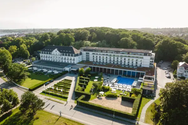 The large white spa centre building with a swimming pool and trees.