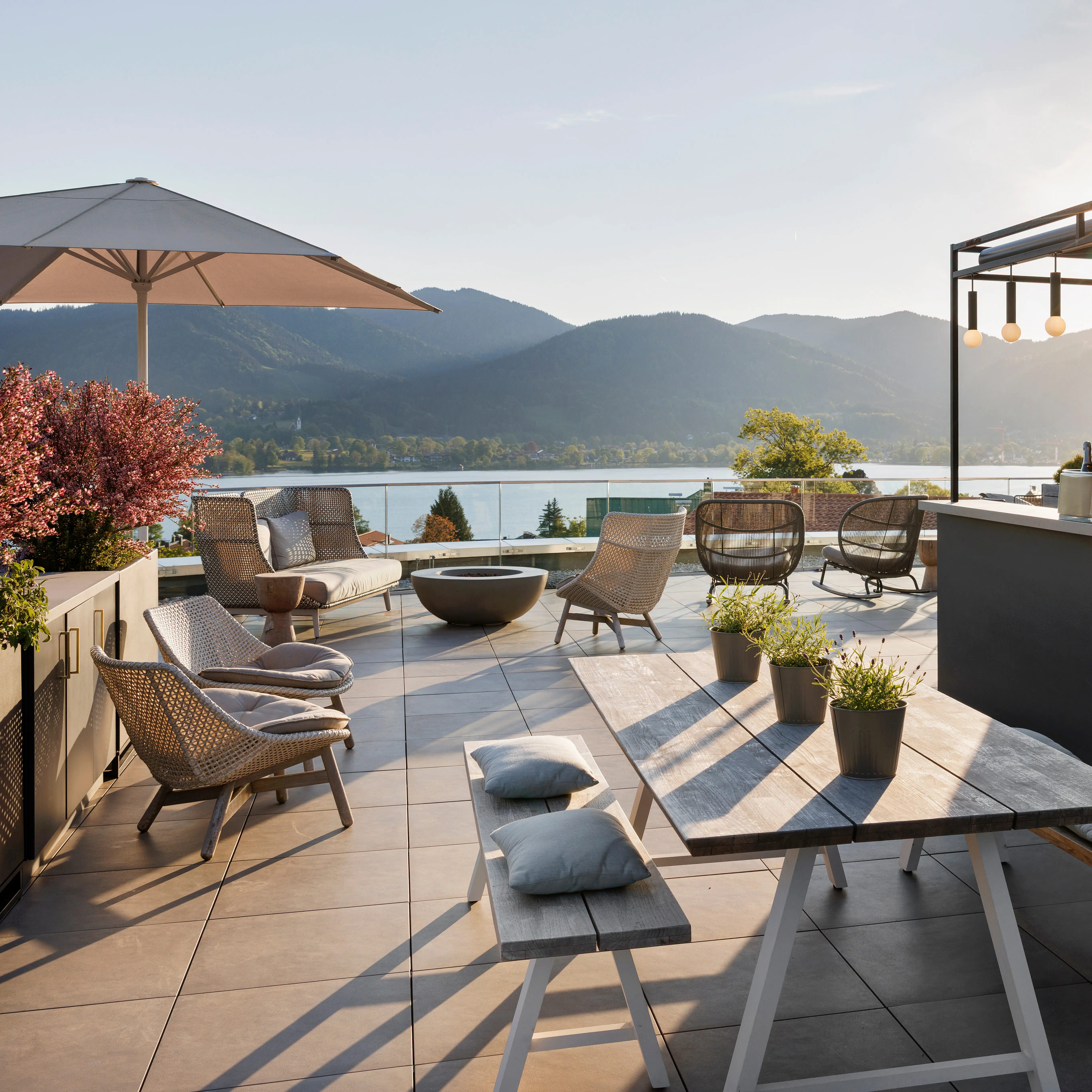 A terrace with a table and chairs, a bar and a view of a lake.