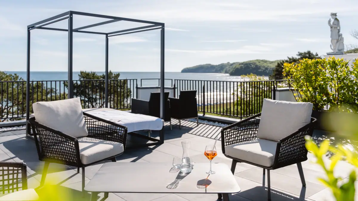 Ein Tisch und Stühle auf einer Terrasse mit Blick auf ein Gewässer.