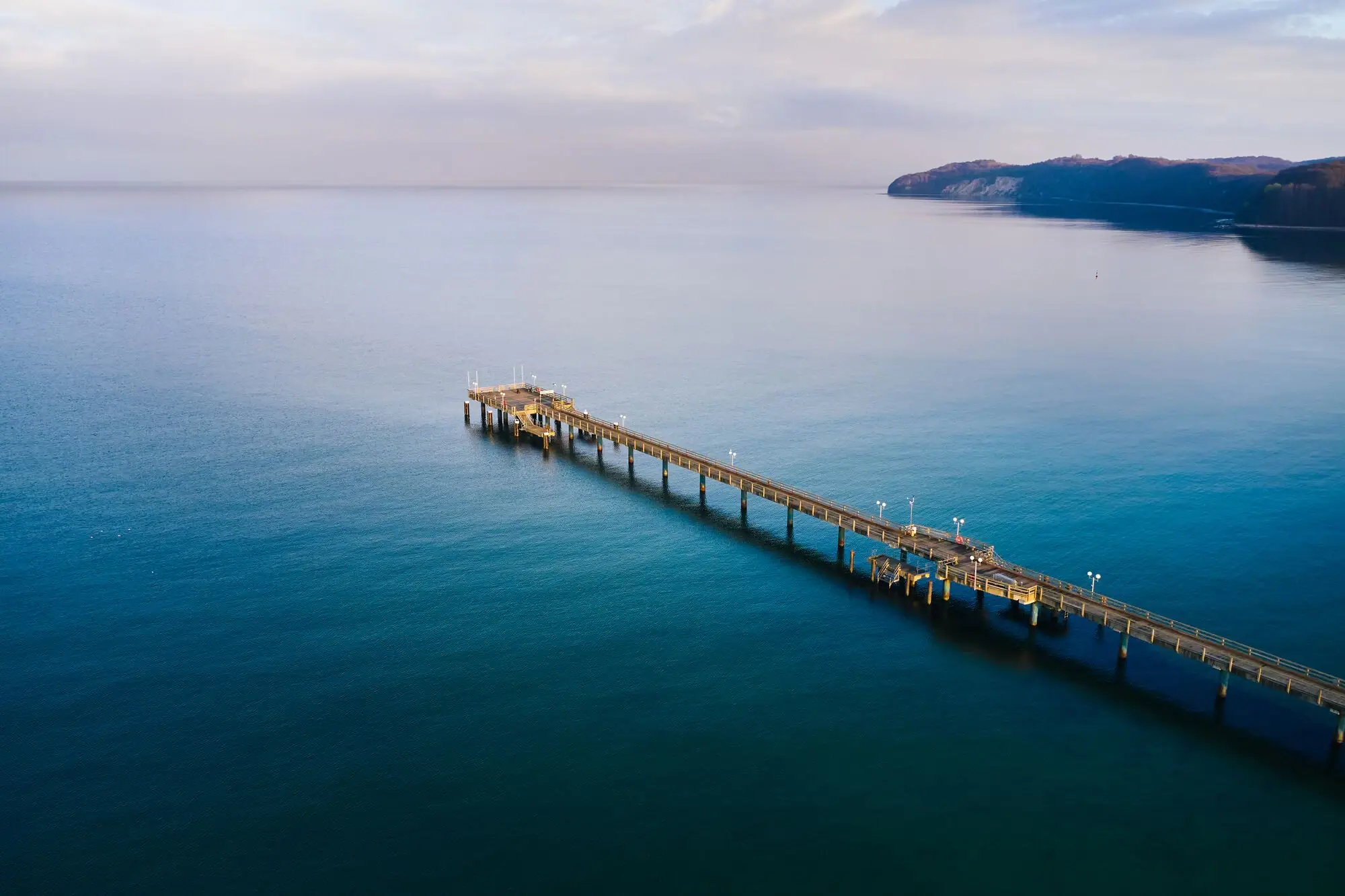 4=3 A long dock extending into a body of water under a cloudy sky.