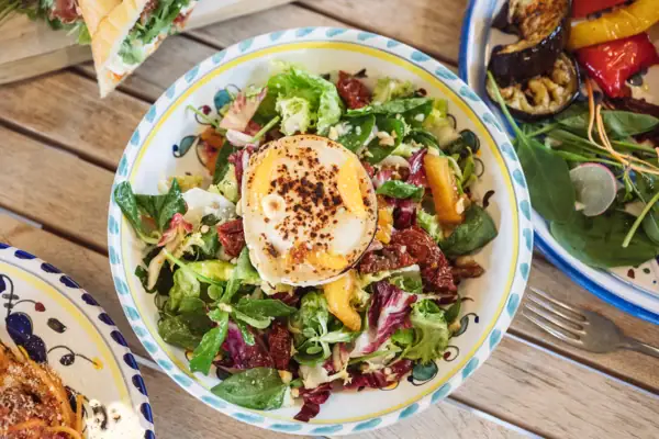 Eine Schüssel Salat mit einem Ei darauf.