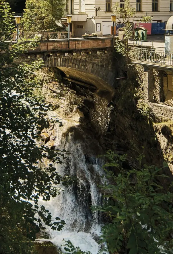 Bridge over a precipice with a waterfall surrounded by trees.