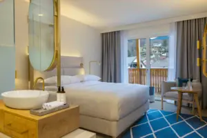 Sleeping area with open-plan bathroom Bedroom with large bed, chair and large mirror.