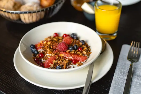 Yoghurt A bowl of fruit and muesli next to a glass of juice.