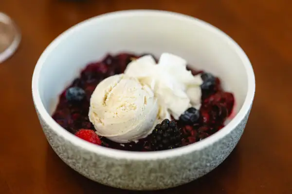 Eine Schüssel mit Obst und Eiscreme auf einem Tisch.