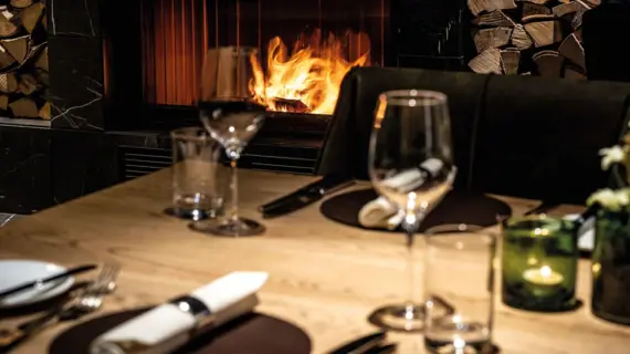 A table with wine glasses and a fire in the background.