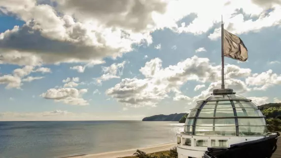 Dome-topped building by a body of water with clouds in the sky.