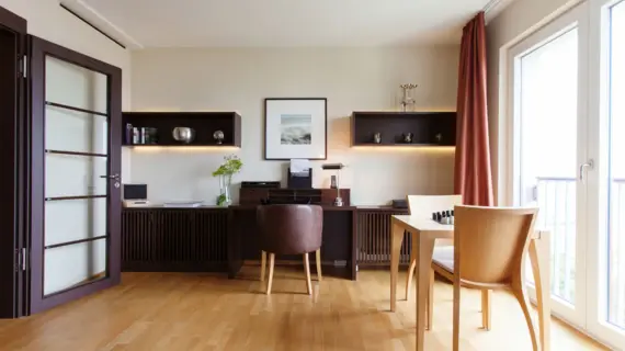 A living area with a dark wood desk and a small light-colored table by the window. 