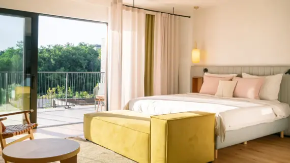 Bedroom featuring a bed with duvet cover and pillows, alongside a couch and a nightstand.