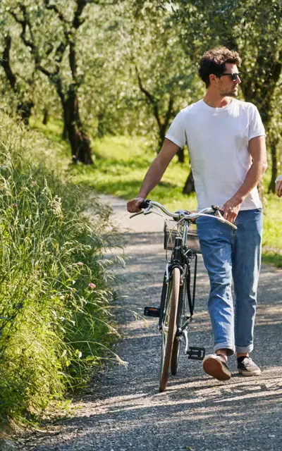 A man and a woman walk with bicycles on a path.