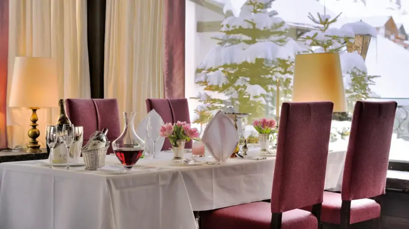 Four red chairs are placed around a laid table with a white tablecloth.