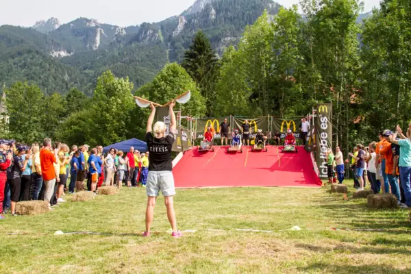 A woman holds a skateboard in the air.