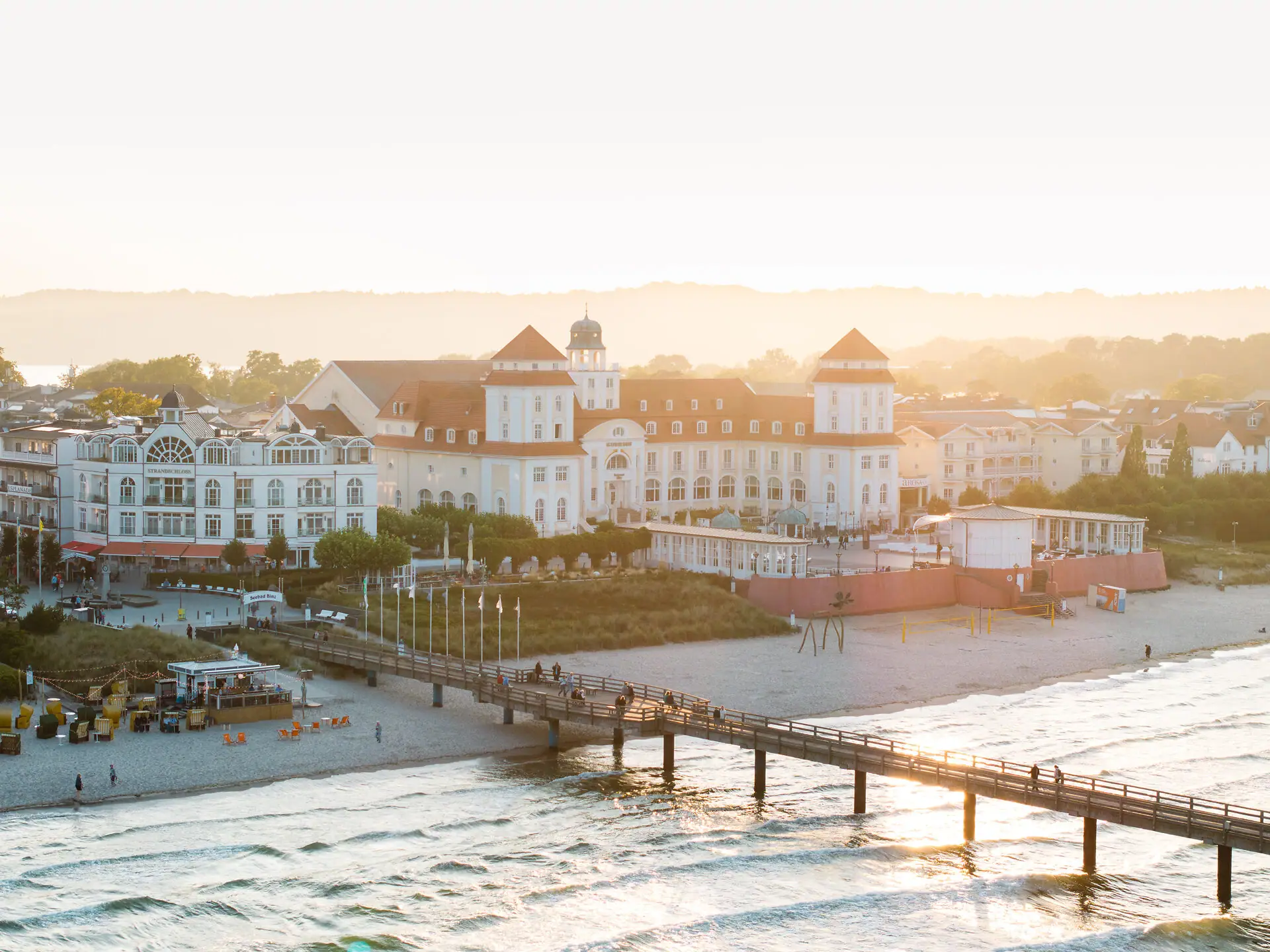 A-ROSA Kurhaus Binz A pier above a beach with buildings and a body of water in winter.
