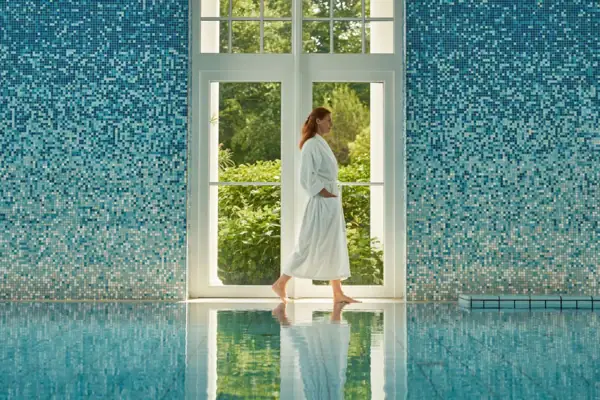 A woman in a white robe walking in a pool.