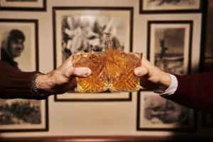 Two hands are holding glasses from which liquid is spurting.