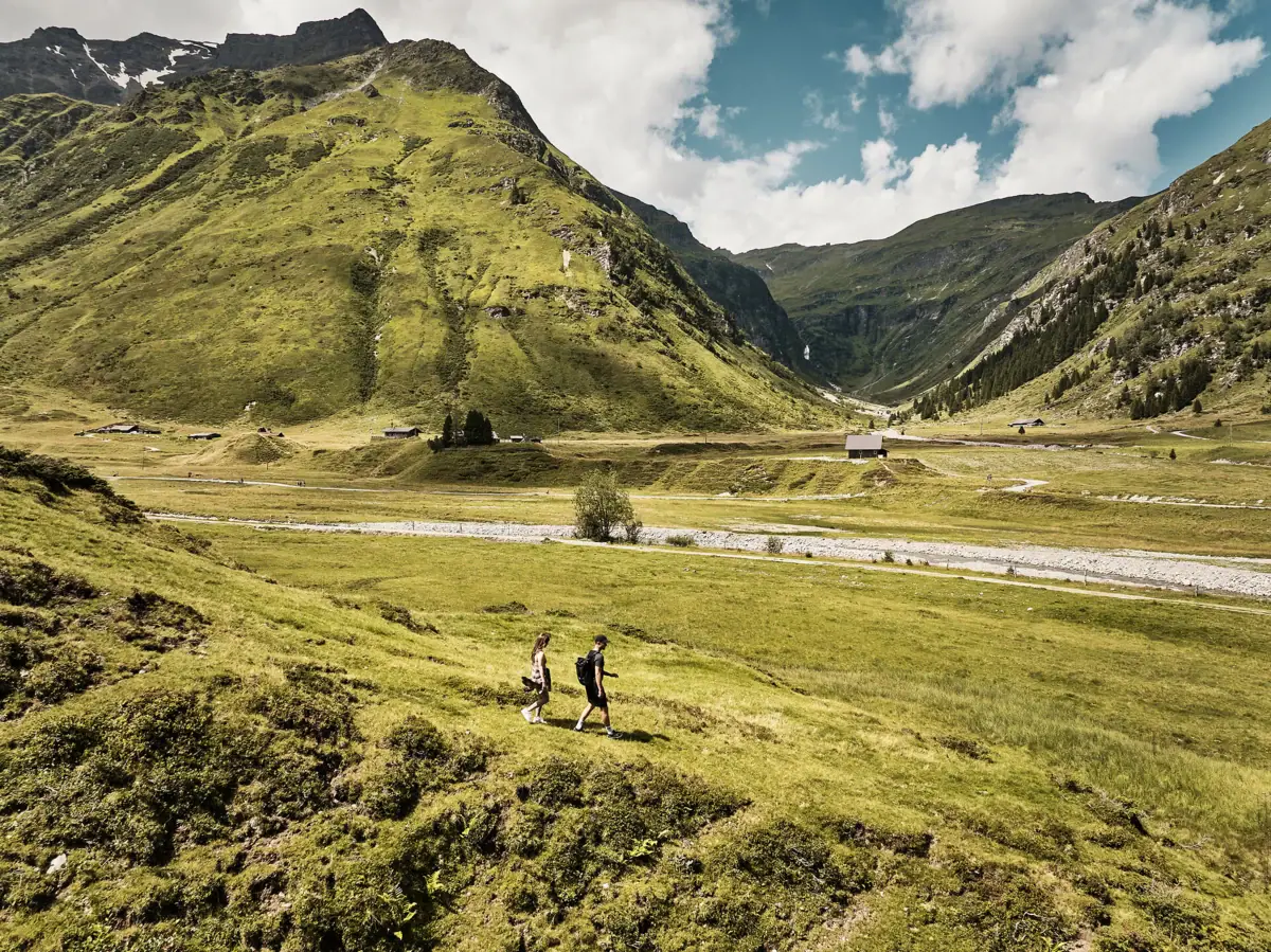 The area around Bad Gastein People are walking in an open, grassy field.
