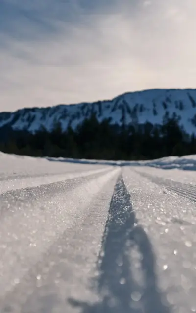 Snow-covered ground with ski tracks and mountain landscape in the background.