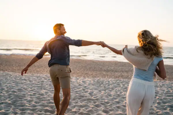 Ein Mann und eine Frau halten Händchen am Strand.