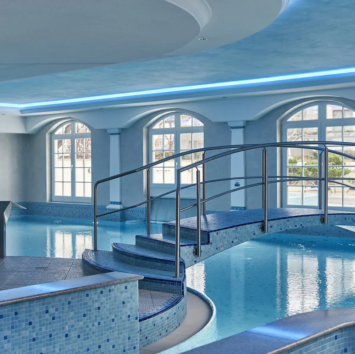 Indoor pool with arched bridge at SPA-ROSA wellness area.