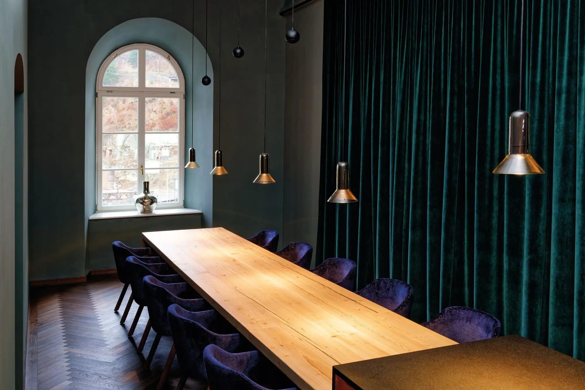 A room with a long table surrounded by chairs.