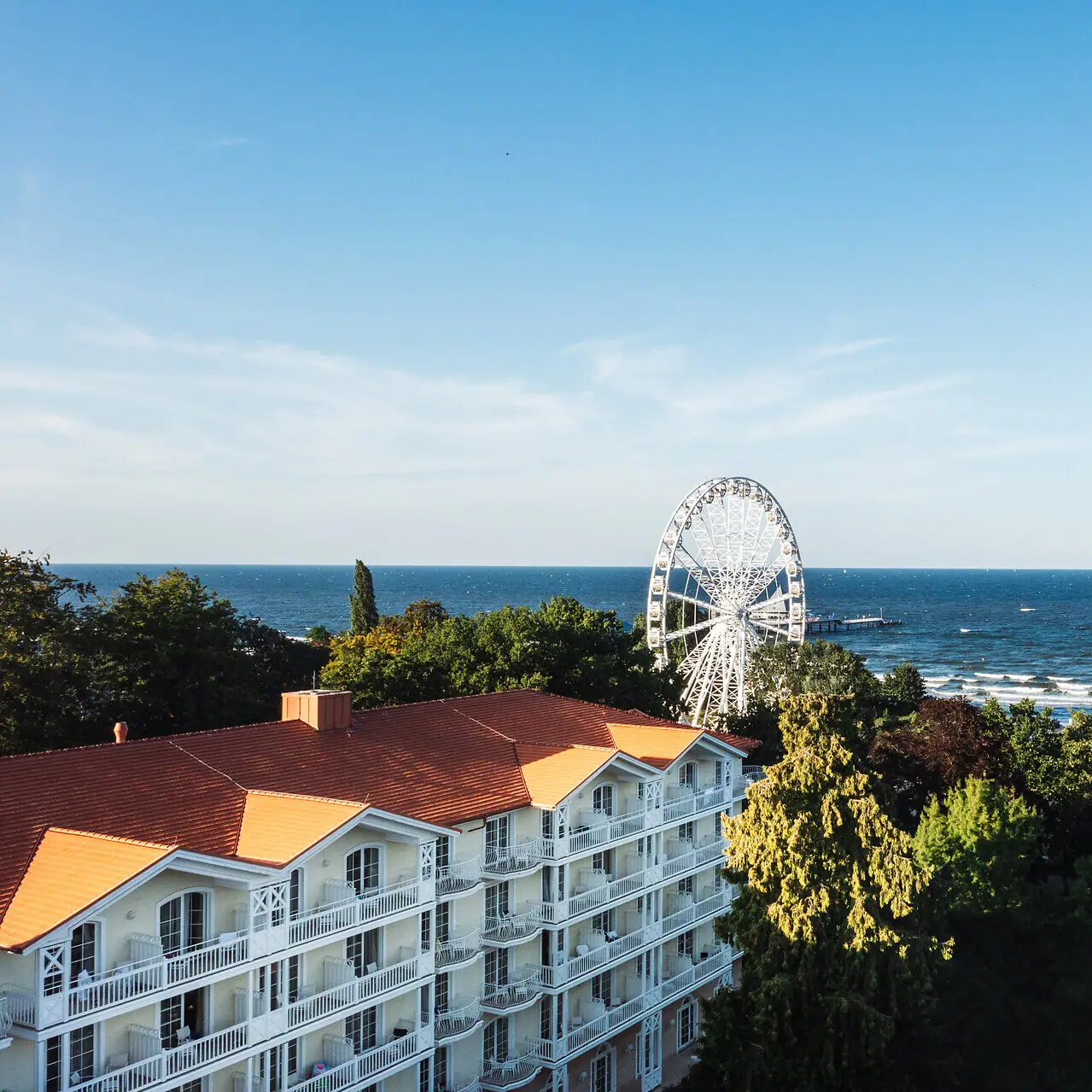 Riesenrad in der Ferne hinter Bäumen und Wasser.