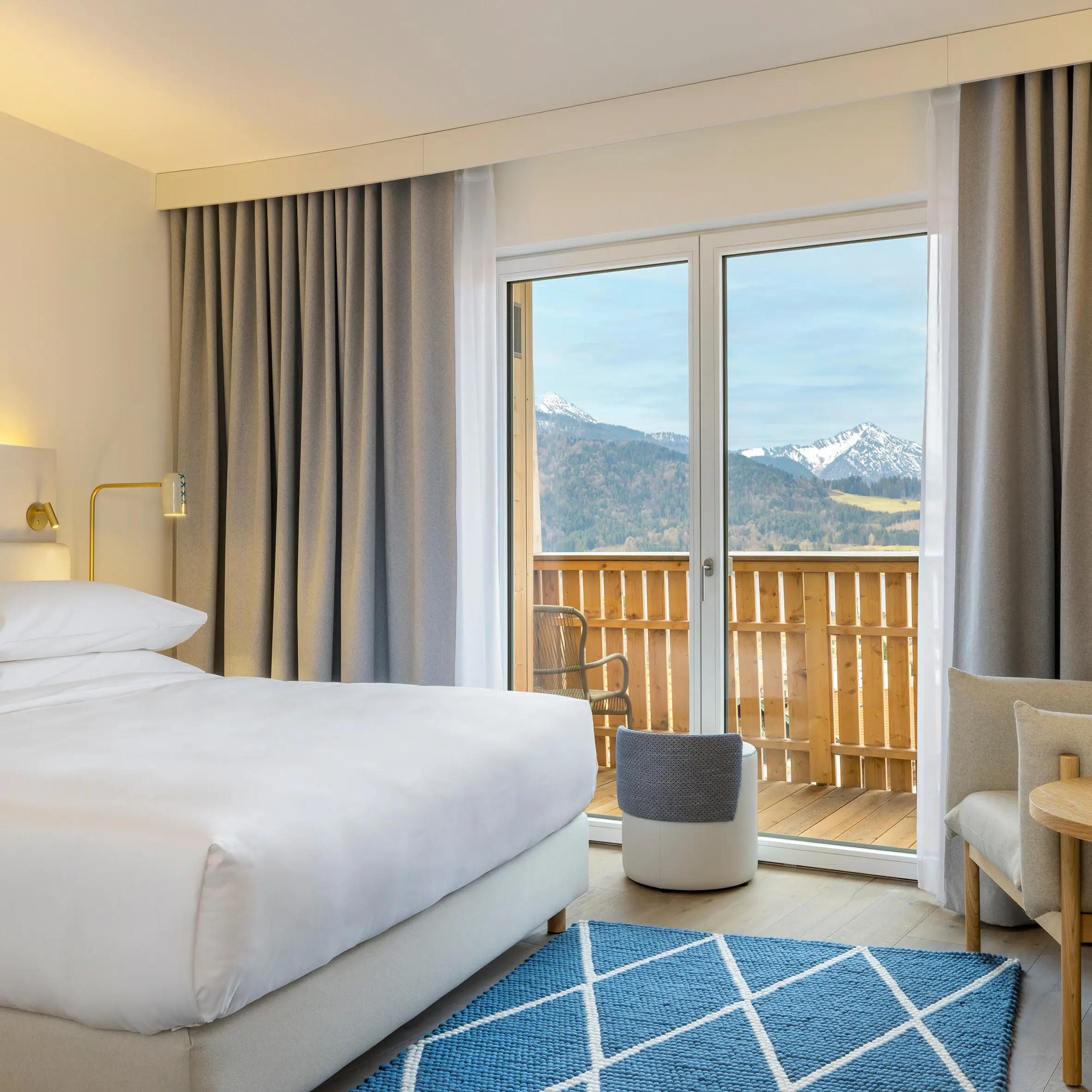 A hotel room at the A-ROSA Tegernsee with a bed, a sofa and a small table.