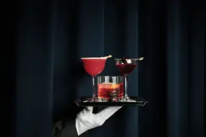 A hand is holding a tray with drinks on it.