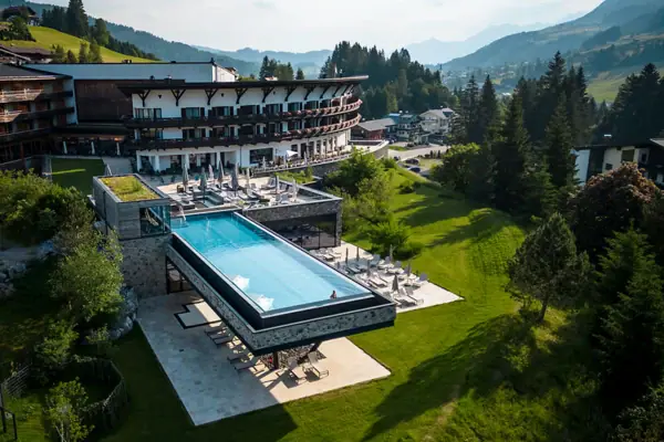 Outdoor pool of a hotel with a view of trees and sky.