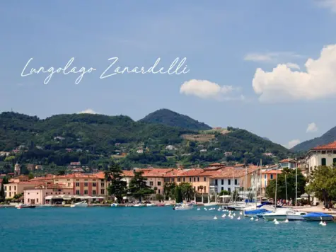 A lake with surrounding buildings and several boats on the water.