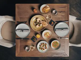 Wooden table with several plates full of appetizers from a bird's eye view.