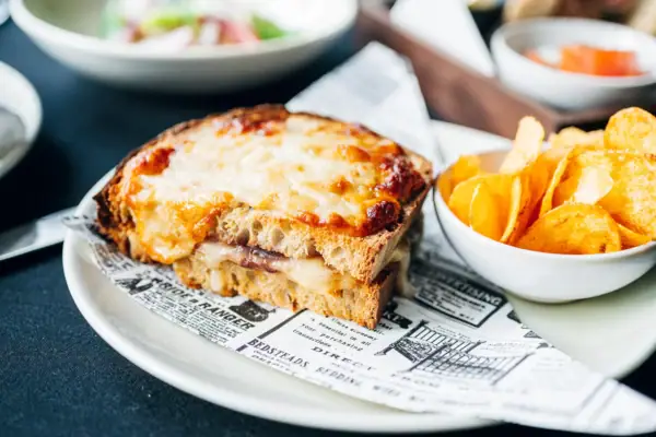 All-Day-Ding Dish A sandwich with cheese and potato chips on a plate.