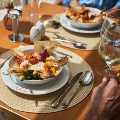 Plate of food with tableware and a wine glass on a table.