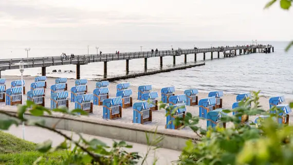 Beach chairs on a beach with a jetty and people.