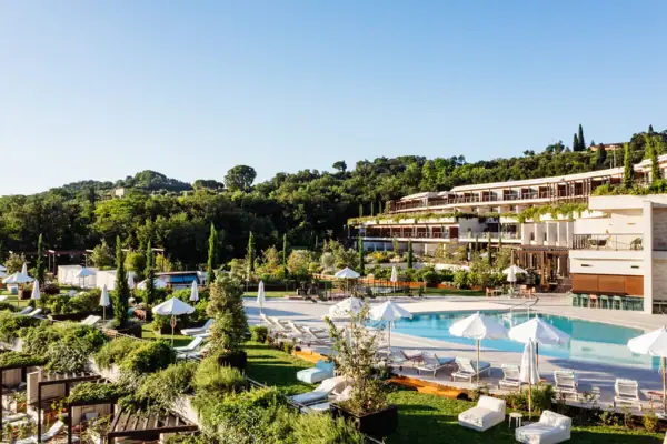Ein Swimmingpool mit Sonnenschirmen und Liegestühlen vor einem Gebäude.