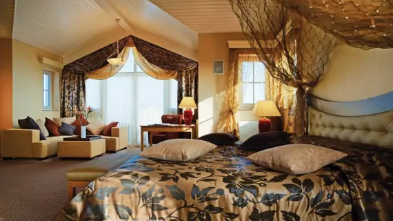 Bedroom with a bed and large window, elegantly designed with soft bedding and decorative pillows.