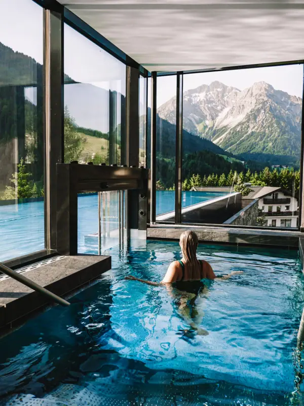A woman in a swimming pool with mountains in the background.