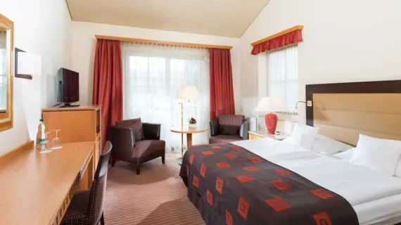 Interior view of a hotel room with a bed and a television.