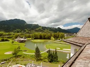 View from a rooftop of a golf course with a lake and the surrounding mountain panorama.