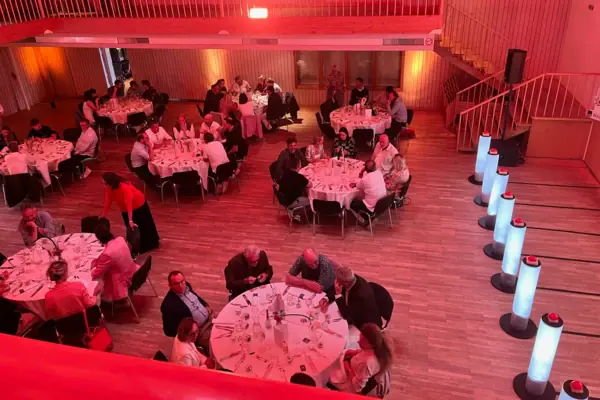 Group of people sitting at tables in a room with red light