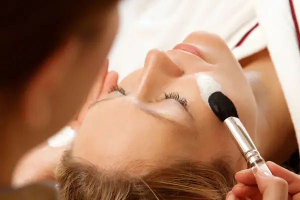 Einer Frau wird eine Creme mit einem Pinsel aufgetragen.