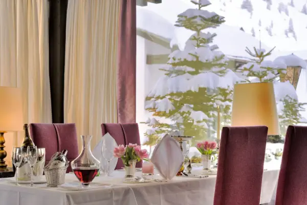 Four red chairs are placed around a laid table with a white tablecloth.